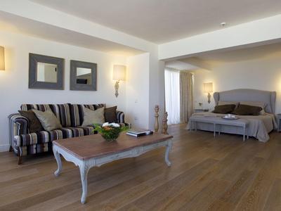 Chambre d'hôtel spacieuse avec canapé, table en bois et lit confortable sur parquet.