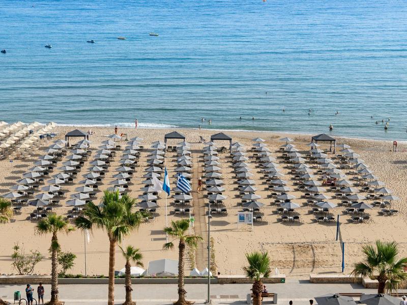 Plage avec rangées de parasols et chaises longues au bord d'une mer calme