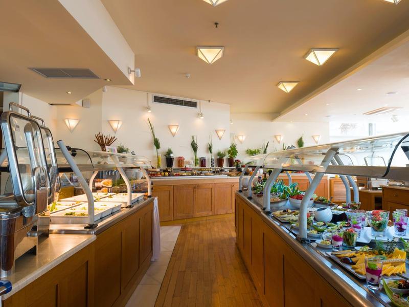 Salle à manger d'hôtel bien éclairée avec stations de buffet et large choix de plats.