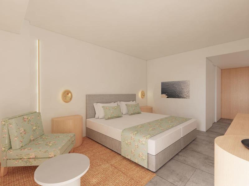 Chambre d'hôtel lumineuse avec lit double, fauteuil, table et décoration moderne.