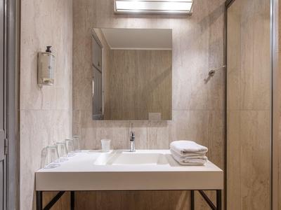 Moderní hotelová koupelna se dřezem, zrcadlem a složenými ručníky.