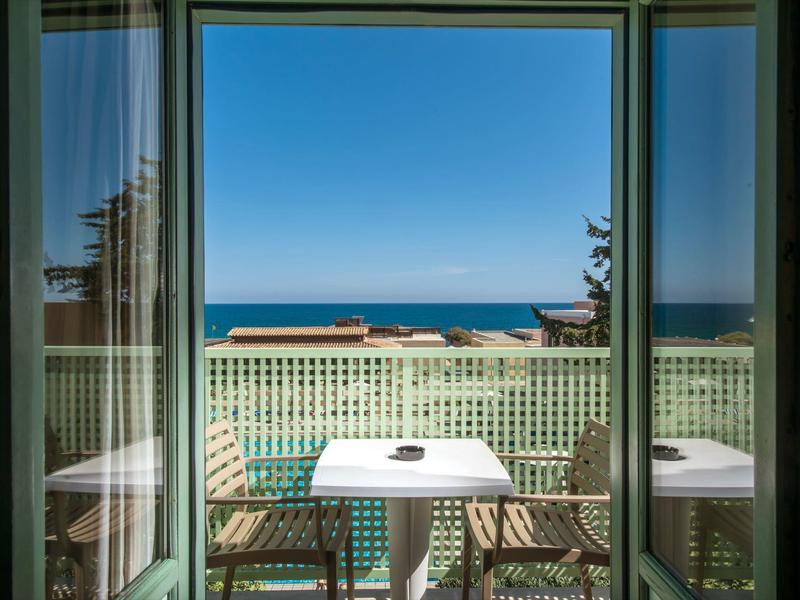 Balkon z stołem i krzesłami z widokiem na ocean i niebieskie niebo.