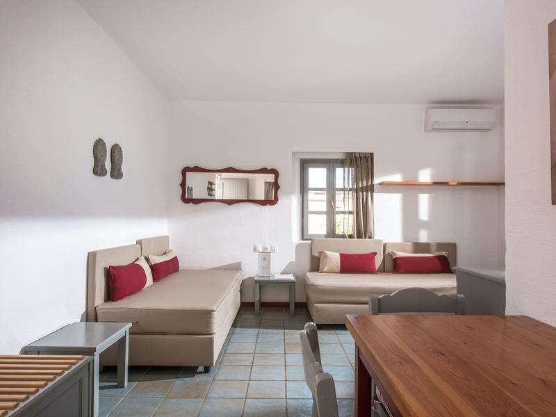 Nowoczesny salon z beżowymi sofami, czerwonymi poduszkami, drewnianym stołem i ozdobnym lustrem.