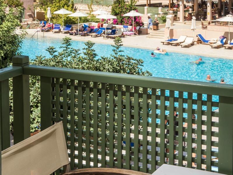 Basen w ośrodku z leżakami, parasolami i budynkami nad morzem w słoneczny dzień.