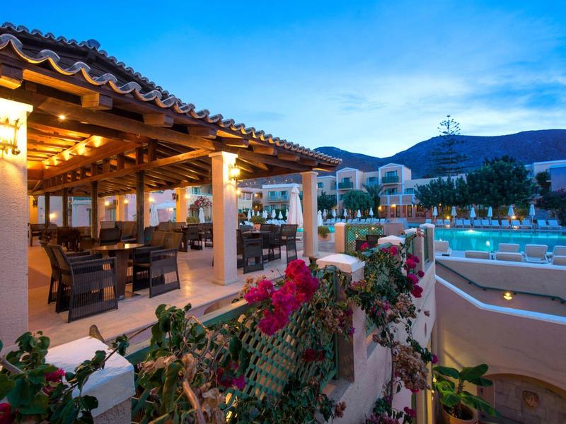 Zewnętrzny taras z ciepłym oświetleniem obok basenu pod głębokim niebieskim wieczornym niebem.