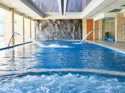 Piscina interior con agua tibia, cascadas y ambiente relajante en un hotel.