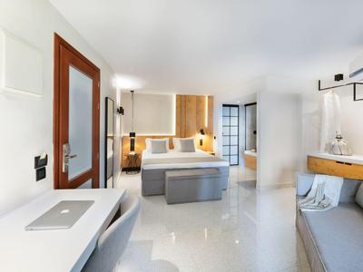 Habitación de hotel moderna y luminosa con cama elegante, escritorio y área de estar.