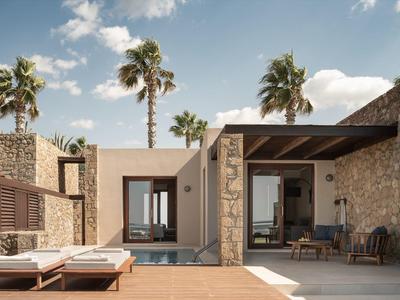 Área de terraza moderna del hotel con tumbonas y vista al mar bajo cielo azul.