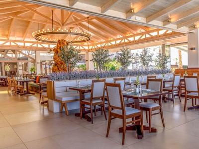 Restaurante de hotel luminoso con muebles de madera y decoración natural bajo un techo de vigas de madera.
