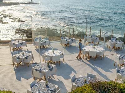 Terraza con varias mesas preparadas junto al mar en un hotel.