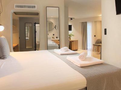 Habitación de hotel moderna con cama doble, colores neutros y diseño minimalista.