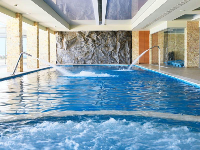Piscina interior con agua tibia, cascadas y ambiente relajante en un hotel.