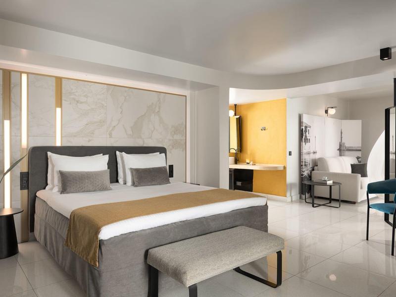 Habitación de hotel moderna con cama doble grande y elegante área de baño abierta.