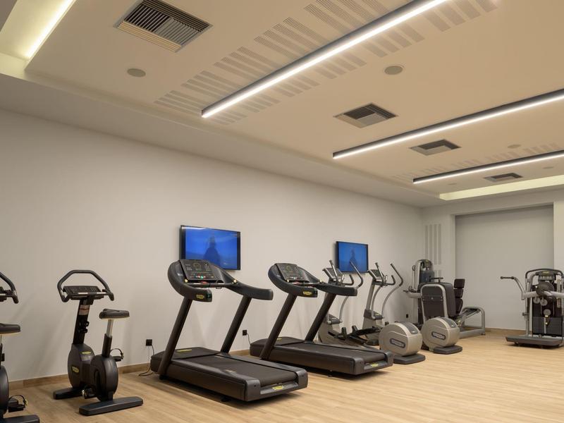 Gimnasio moderno con cintas de correr, bicicletas y máquinas elípticas en un hotel.