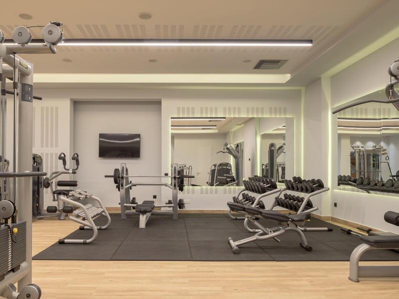 Sala de fitness moderna con banco de pesas, mancuernas y equipos de entrenamiento en un hotel.