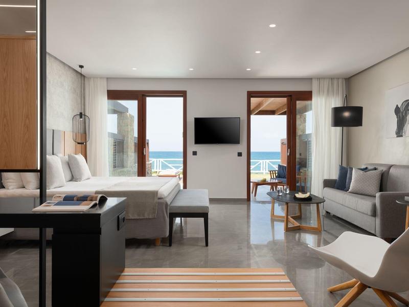 Habitación de hotel moderna con vista al mar, cama doble y zona de estar.