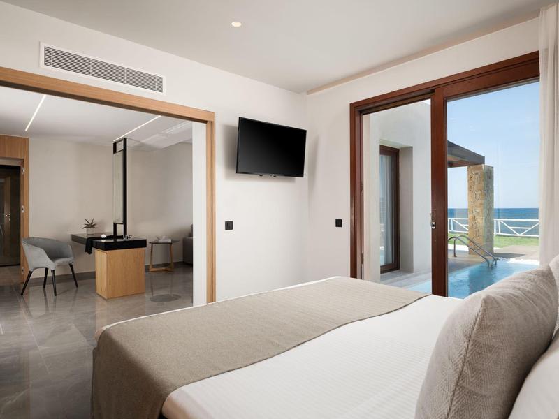 Habitación de hotel moderna con cama doble, TV y vista a terraza con vista al mar.