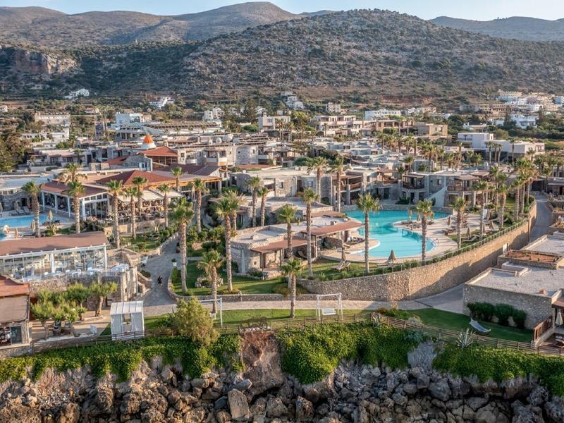 Resort hotel con varias piscinas frente a paisaje montañoso y cielo despejado a la luz del día