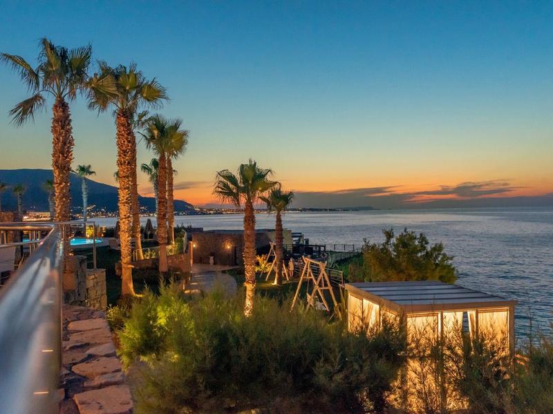 Atardecer en un hotel con palmeras y vista al mar.