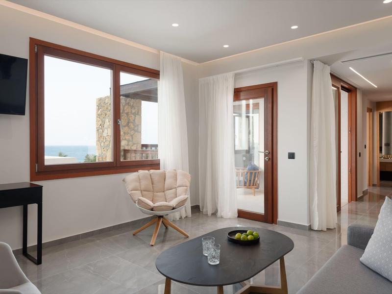 Sala moderna con ventana grande, mesa de centro, sillas y decoración minimalista en tonos neutros