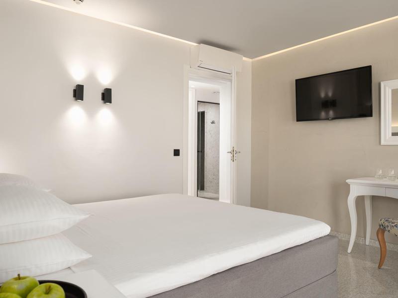 Habitación de hotel moderna con cama grande, televisor en la pared y elegante escritorio con silla.