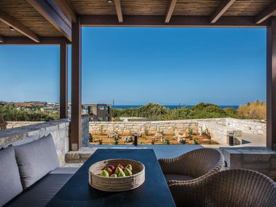 Moderner Lounge-Bereich mit Pool und Aussicht auf das Meer an sonnigem Tag.
