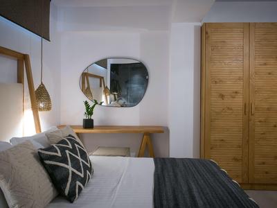 Modern eingerichtetes Hotelzimmer mit Bett, Kissen, Nachttischlampe und Holzschrank.
