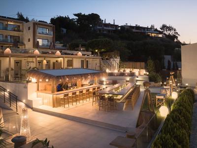 Verlichte hotelbar met zitplaatsen in een modern buitengebied bij schemering.