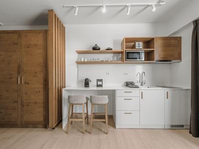 Moderne Hotelküche mit Holzelementen, Barhockern und eleganter weißer Arbeitsfläche.