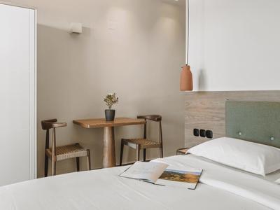 Modern, simply furnished hotel room with bed, nightstand, and dining area.