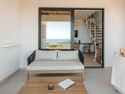 Modern balcony with sofa, table, and sea view through large windows.