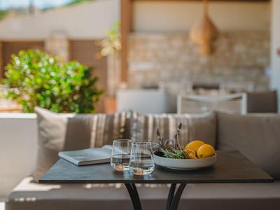 Moderne buitenruimte met tafel, glazen, fruitschaal en gezellige bank op de achtergrond.