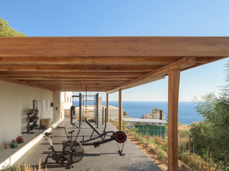 Outdoor gym under wooden pergola with sea view and clear sky