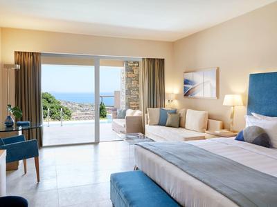 Světý hotelový pokoj s manželskou postelí, posezením a výhledem na moře přes velká okna