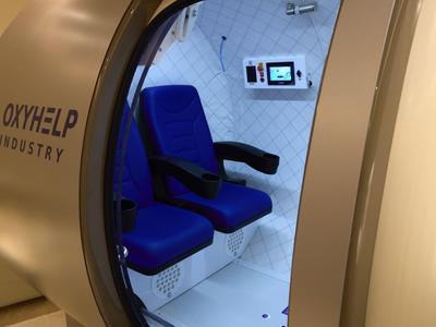 Kapslová relaxační kabina s modrými sedadly a ovládacím panelem pro hotely nebo wellness.