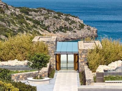 Moderní kamenný vstup se sklem s výhledem na hornatý pobřeží a moře