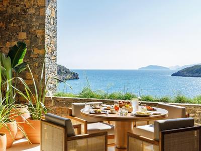 Terrasse avec table et chaises donnant sur la mer et les montagnes par une journée ensoleillée