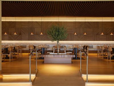 Moderner Hotelrestaurant-Eingang mit großem Blumenarrangement und Holzverkleidung.