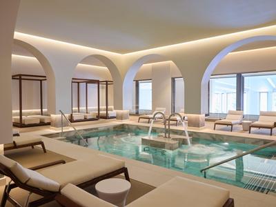 Moderner Innenpool mit Liegestühlen, großen Bögen und sanfter Beleuchtung in einem Hotel.