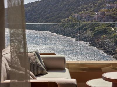 Pohodlný sedací kout na terase s výhledem na pobřeží a moře za slunečného počasí.