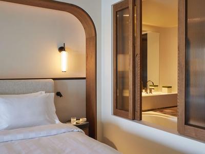 Gemütliches Hotelzimmer mit modernem Bett und Fenster zum Badezimmer.