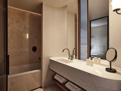 Moderní koupelna s mramorovou vanou a umyvadlem s velkým zrcadlem.