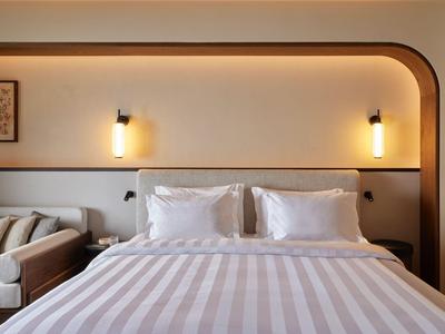 Modernes Hotelzimmer mit großem Bett, gestreifter Bettwäsche und Sofa an der Wand.