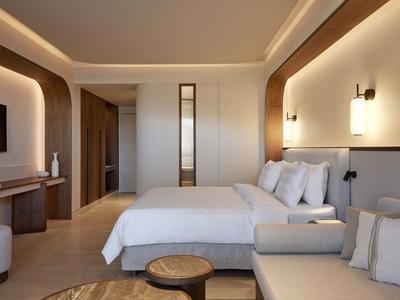 Modernes Hotelzimmer mit großem Bett, gemütlicher Couch und warmem Licht.