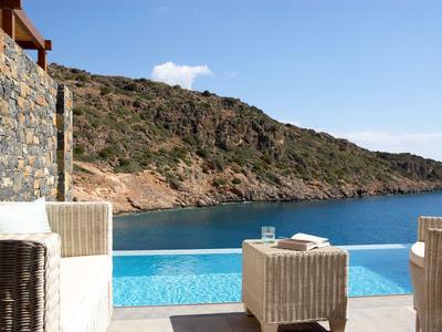 Moderne Terrasse mit Pool und Blick auf das Meer und felsige Hügel.