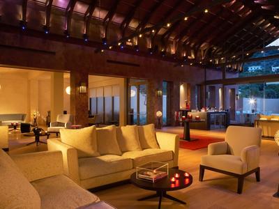 Gemütlicher Hotel-Loungebereich mit Sofas, Sesseln und warmer Beleuchtung unter einem Holzdach.