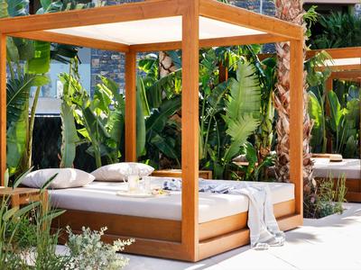 Gemütliche Betten mit Holzrahmen im tropischen Garten für Entspannung im Freien.