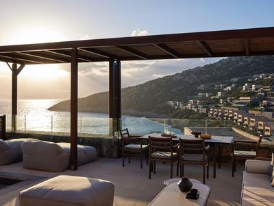 Terrazza con posti a sedere e vista sul mare e sulle montagne al tramonto.