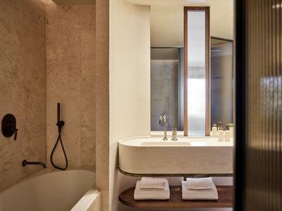 Modernes Badezimmer mit Badewanne, Waschbecken und großem Spiegel in warmen Farbtönen.