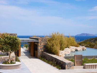 Moderner Außenbereich eines Hotels mit Pool, Gehwegen und Blick auf das Meer.
